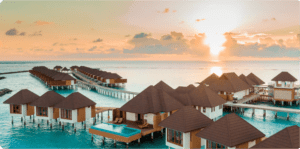 Overwater bungalows at sunset with a serene ocean view.