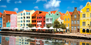 Colorful buildings reflecting on calm water under a blue sky.
